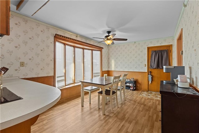 dining room with light wood-type flooring, ceiling fan, and wooden walls