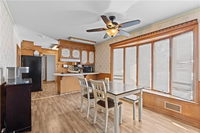 dining room featuring light hardwood / wood-style floors, ornamental molding, ceiling fan, and a healthy amount of sunlight