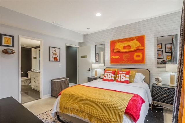 carpeted bedroom featuring brick wall and ensuite bath