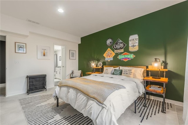 bedroom with concrete flooring and ensuite bath