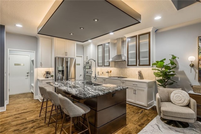 kitchen with white cabinetry, wall chimney range hood, dark wood-type flooring, and appliances with stainless steel finishes