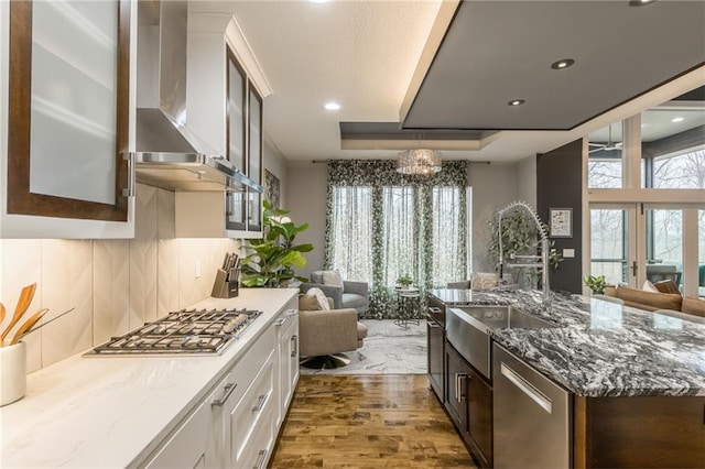 kitchen featuring white cabinetry, dark brown cabinets, stainless steel appliances, and wall chimney exhaust hood