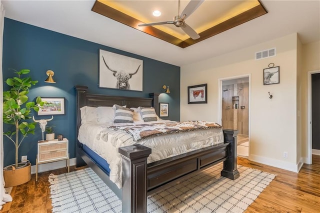 bedroom featuring a tray ceiling, wood-type flooring, and ceiling fan