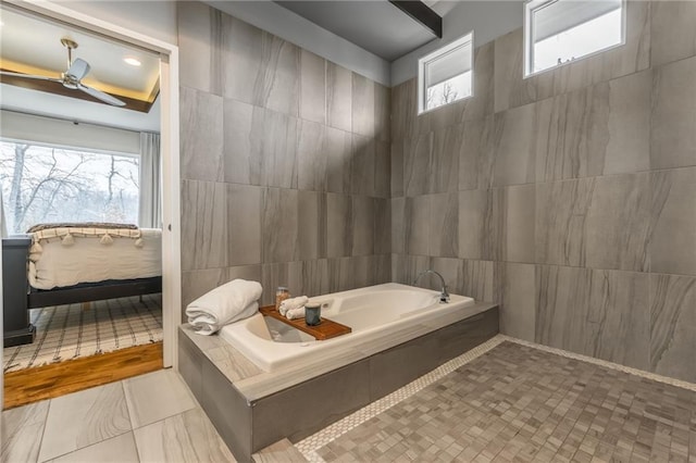 bathroom with tile walls, plenty of natural light, tile patterned floors, and tiled bath