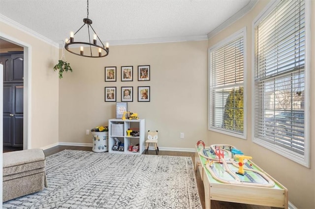 playroom featuring ornamental molding, hardwood / wood-style floors, a textured ceiling, and a notable chandelier