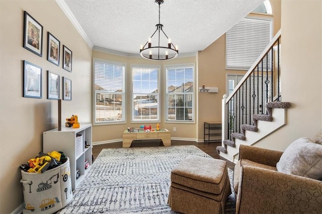 playroom with ornamental molding, dark wood-type flooring, a notable chandelier, and a textured ceiling