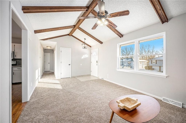 unfurnished living room featuring a textured ceiling, ceiling fan, light carpet, and vaulted ceiling with beams