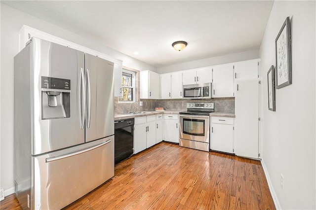 kitchen featuring stainless steel appliances, white cabinets, sink, and tasteful backsplash