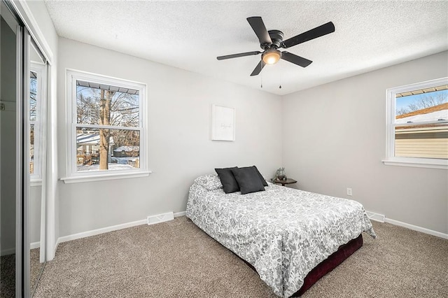 bedroom with multiple windows, ceiling fan, a textured ceiling, and carpet