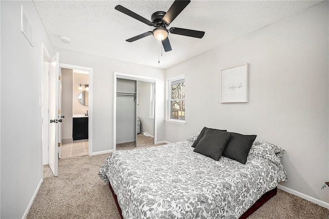 carpeted bedroom with ensuite bathroom, a closet, ceiling fan, and a textured ceiling