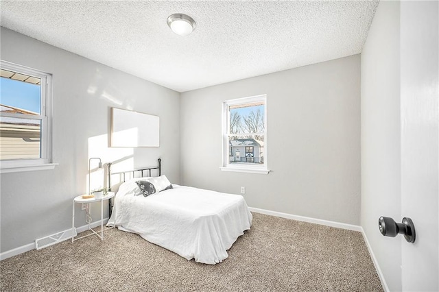 carpeted bedroom with a textured ceiling and multiple windows