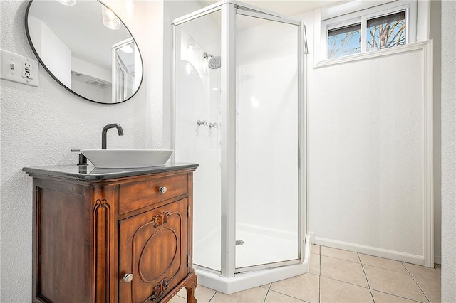 bathroom with a shower with door, vanity, and tile patterned floors