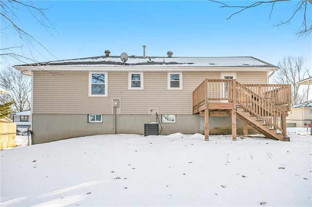 snow covered house featuring central AC unit and a wooden deck