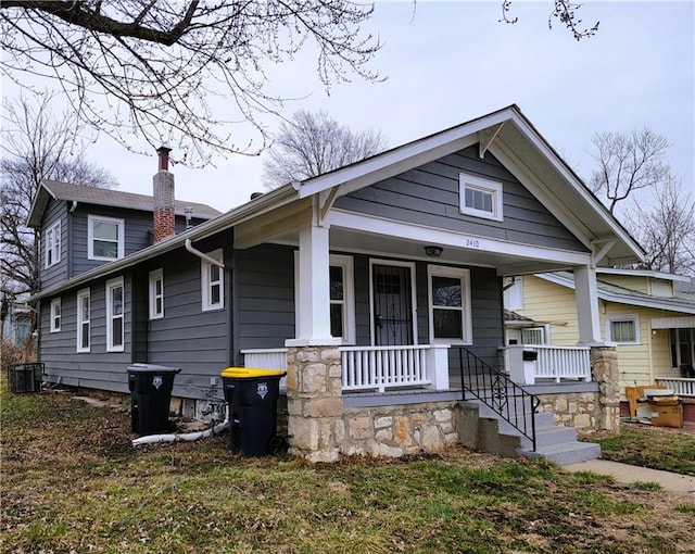 view of front facade featuring central air condition unit, a chimney, and a porch