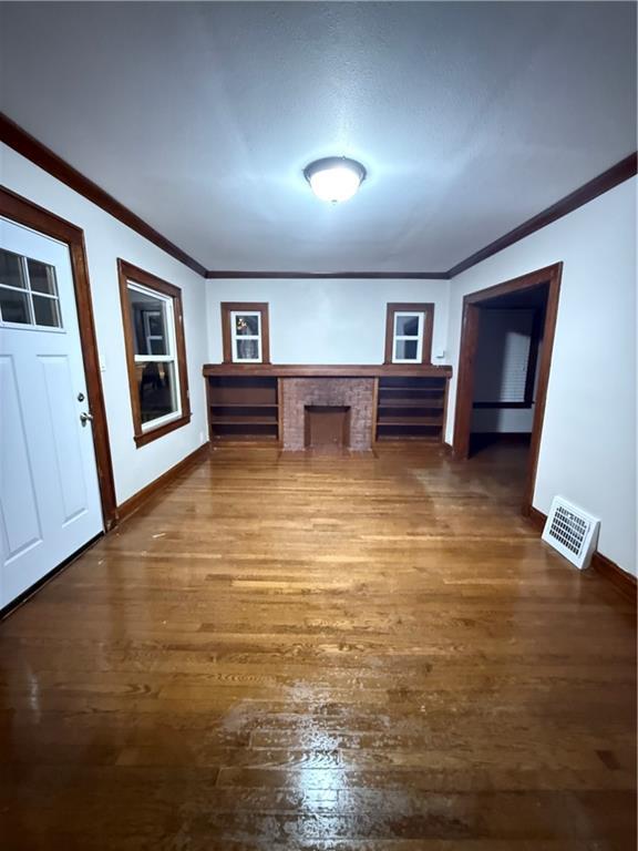 unfurnished office with baseboards, dark wood-style flooring, visible vents, and crown molding