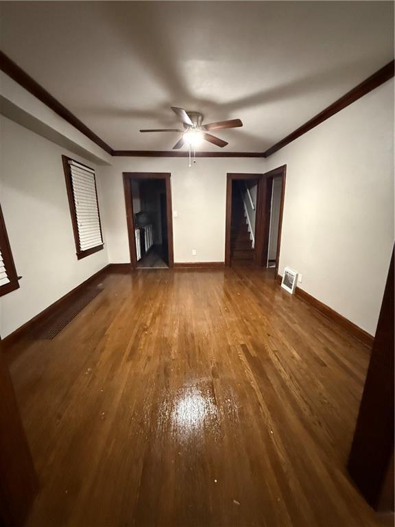 unfurnished living room featuring stairway, ornamental molding, ceiling fan, wood finished floors, and baseboards