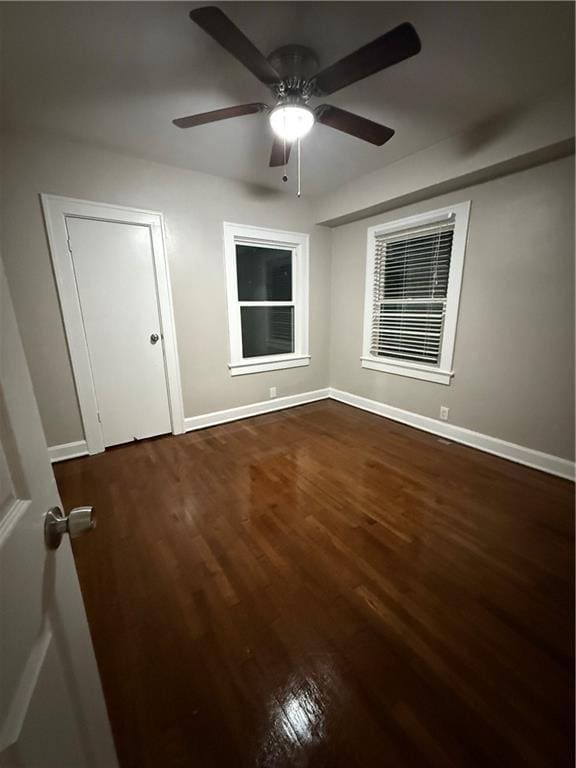 unfurnished bedroom featuring dark wood-style floors, ceiling fan, and baseboards