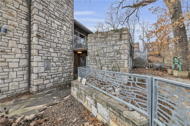 property entrance featuring a balcony and stone siding