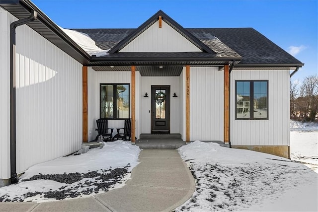 snow covered property entrance with covered porch