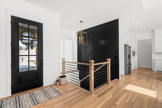 entryway with light hardwood / wood-style floors and an inviting chandelier