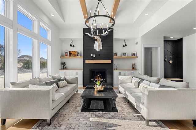 living room with light wood-type flooring, an inviting chandelier, a fireplace, and a high ceiling