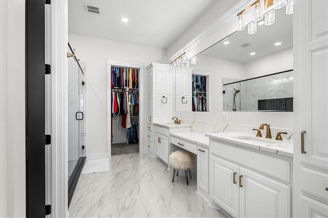 bathroom featuring a shower with door and vanity