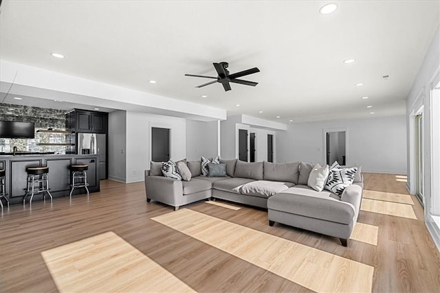 living room featuring light hardwood / wood-style floors, sink, and ceiling fan