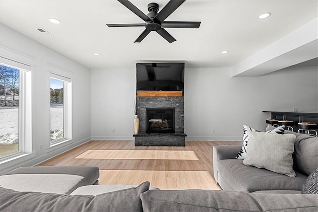 living room with ceiling fan, light wood-type flooring, and a fireplace