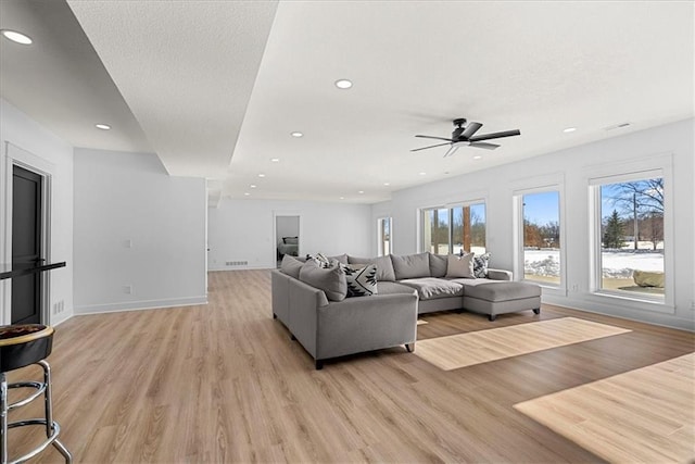 living room with ceiling fan, plenty of natural light, and light hardwood / wood-style flooring