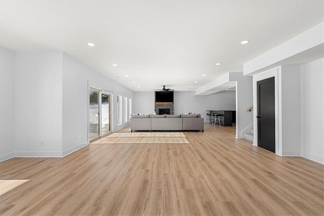 unfurnished living room featuring light hardwood / wood-style floors, a large fireplace, and ceiling fan