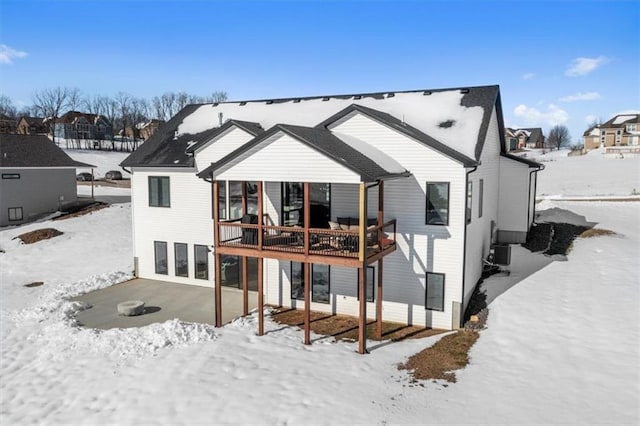 snow covered back of property with cooling unit and a deck