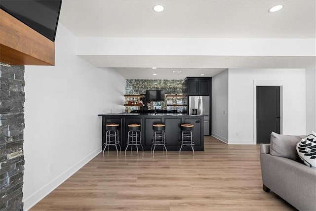 bar with stainless steel fridge with ice dispenser and hardwood / wood-style flooring