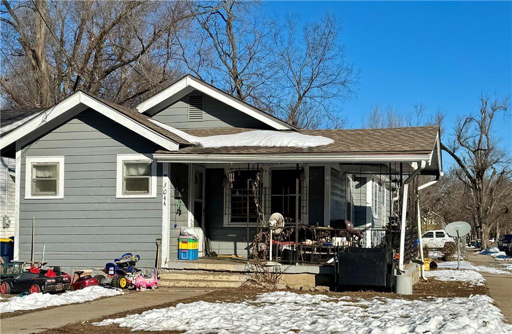 snow covered rear of property with a porch