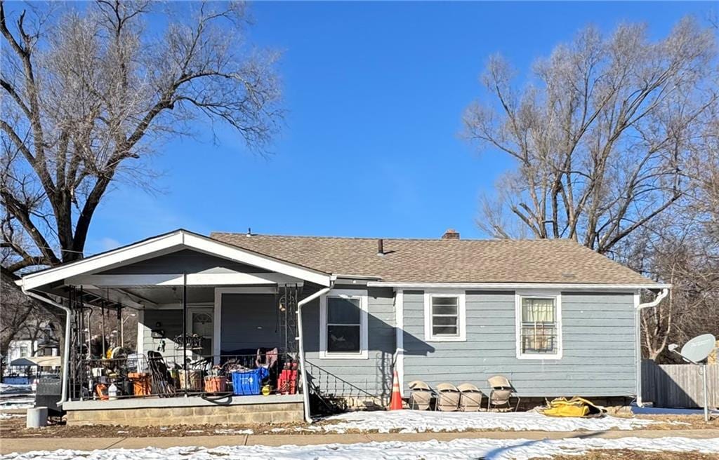 snow covered back of property with covered porch