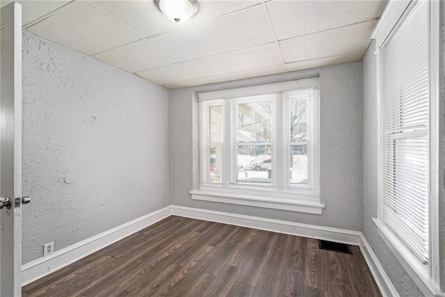 unfurnished room featuring dark hardwood / wood-style flooring and a drop ceiling