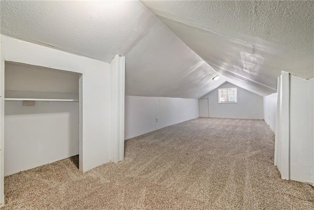 bonus room with vaulted ceiling, light colored carpet, and a textured ceiling