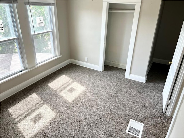 unfurnished bedroom featuring multiple windows, carpet floors, and a closet