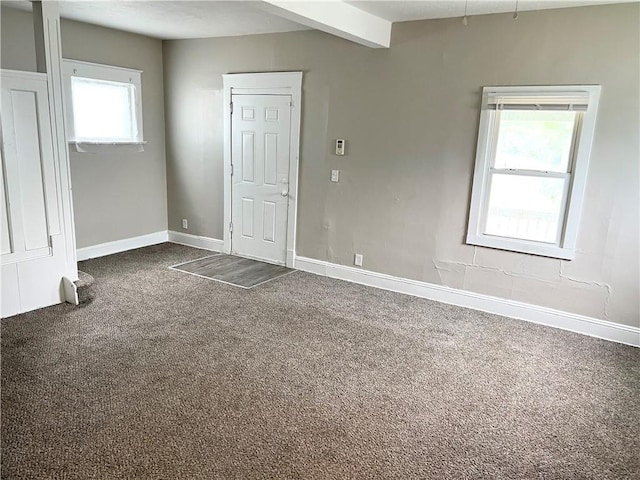 carpeted empty room with beam ceiling