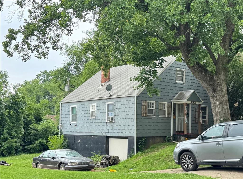 5107 E 40th St, Kansas City, MO 64130 - view of side of property with a chimney, a lawn, cooling unit, and roof with shingles