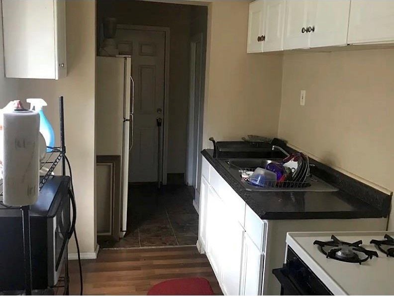 kitchen with dark wood-type flooring, sink, white cabinets, and refrigerator