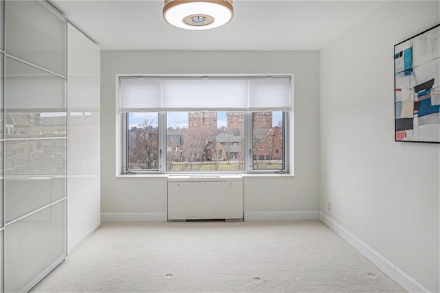 empty room featuring radiator heating unit and light colored carpet