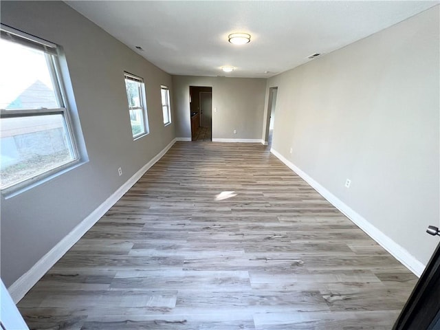 empty room with a wealth of natural light and light hardwood / wood-style flooring