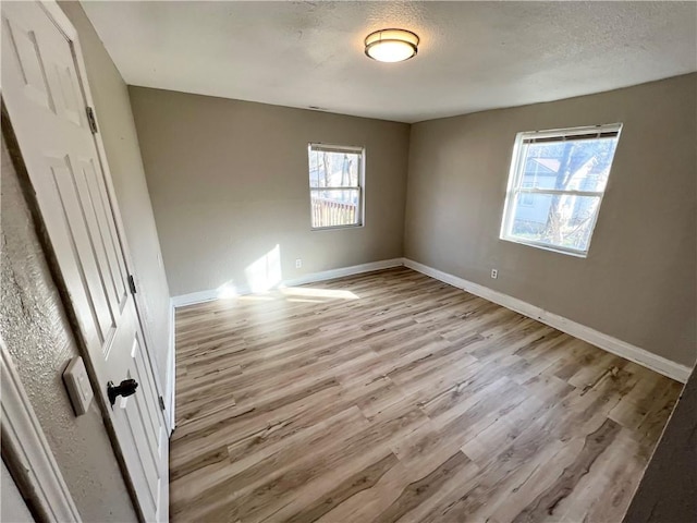 unfurnished bedroom featuring multiple windows, a textured ceiling, and light wood-type flooring