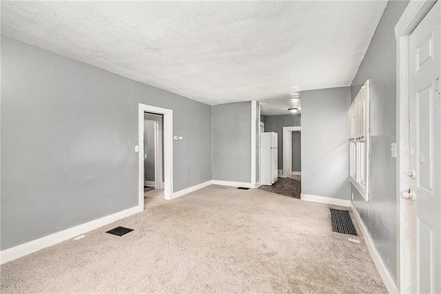 spare room with light colored carpet and a textured ceiling