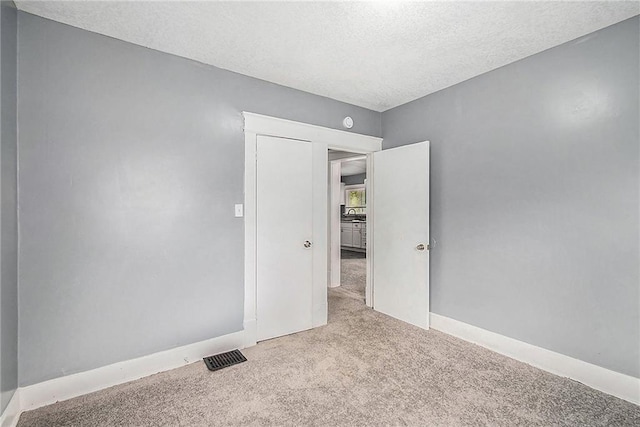 carpeted empty room with a textured ceiling