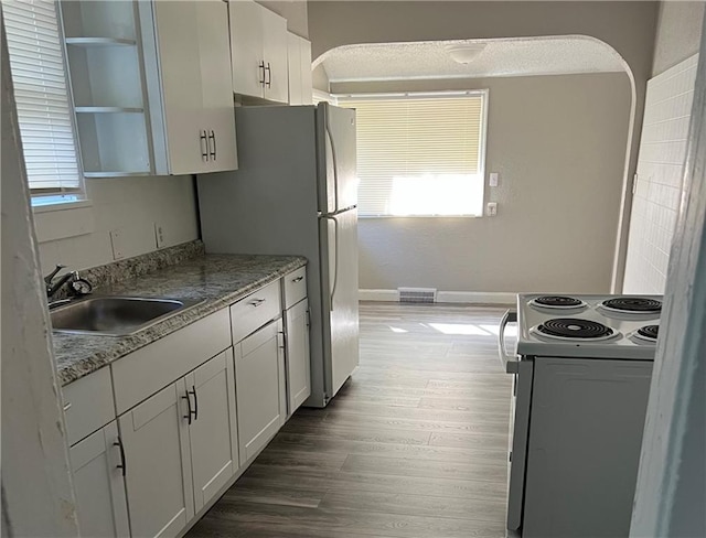 kitchen with sink, white cabinets, hardwood / wood-style flooring, electric range, and light stone counters