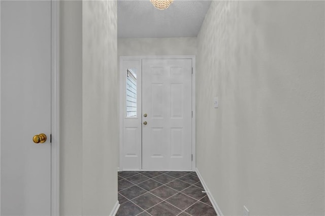 entryway with dark tile patterned flooring and a textured ceiling