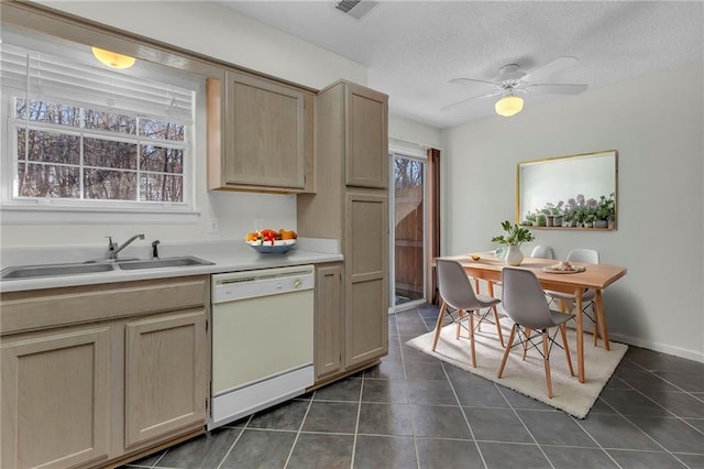 kitchen with sink, white dishwasher, a textured ceiling, dark tile patterned flooring, and light brown cabinets