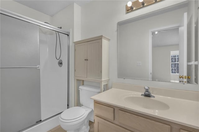 bathroom featuring a shower with door, vanity, and toilet