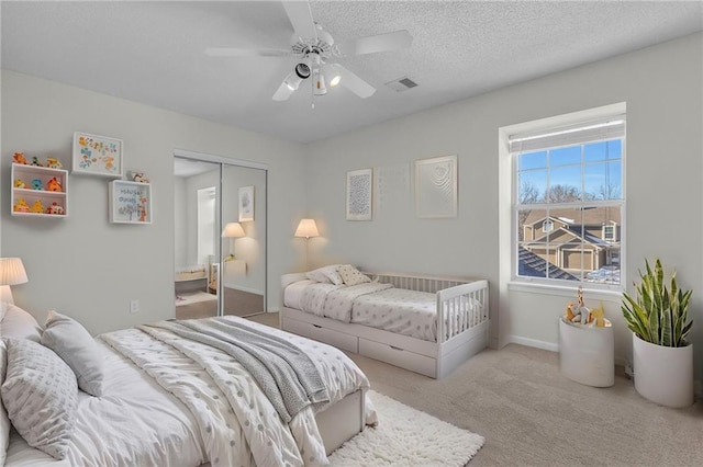 carpeted bedroom featuring a textured ceiling, ceiling fan, and a closet